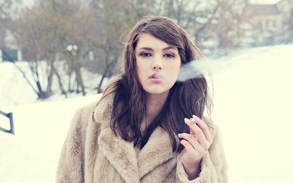 雪の中でコートを着てタバコを吸う女性を撮影した綺麗な写真壁紙画像