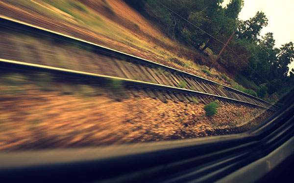 電車の窓から見た勢いよく流れる線路道の迫力の写真