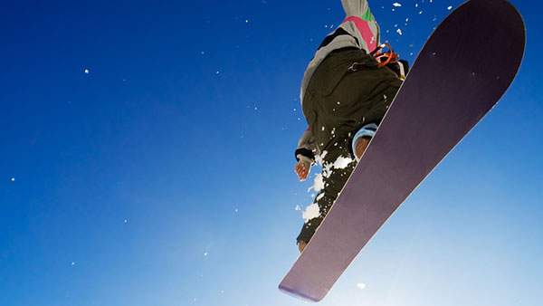 澄み切った青空とスノーボードでジャンプを決める男性の爽やかな写真壁紙