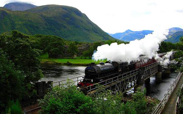 真っ白な煙を上げて山間を進む蒸気機関車の高画質な写真壁紙画像