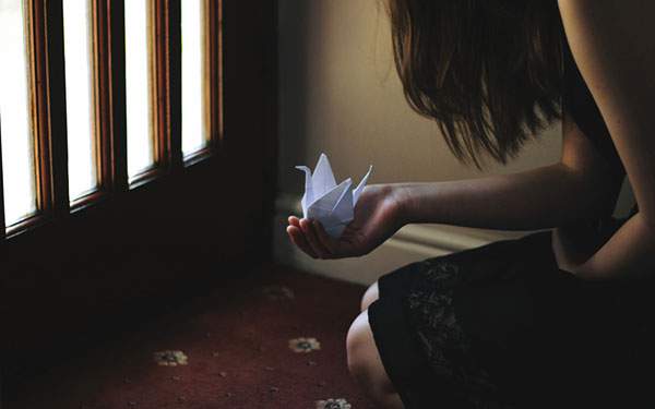 鶴の折り紙を持って座る女性を撮影した綺麗な写真壁紙画像