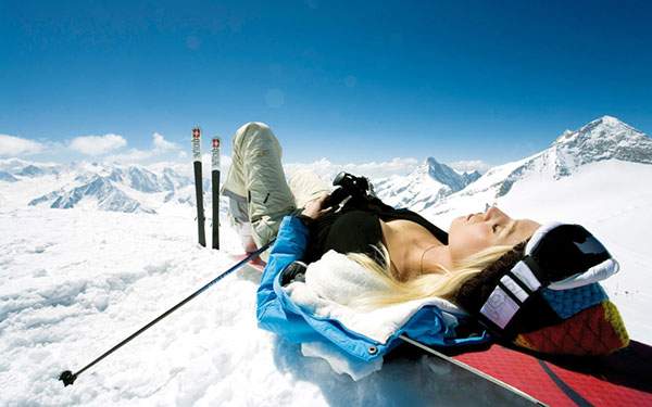 雪山で気持ち良さそうに眠る女性スキーヤーの写真壁紙画像
