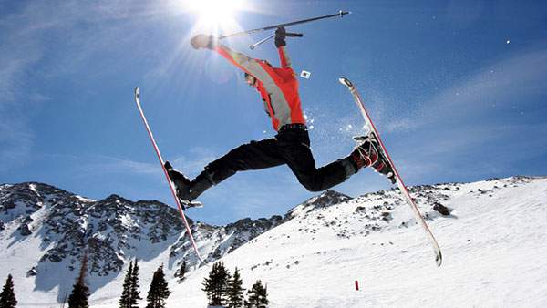 太陽を背にして派手なジャンプを決めるスキーヤーの写真壁紙画像