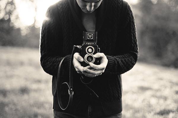 古いカメラを構える男性のモノクロ写真