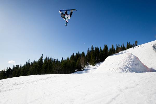 青空をバックにジャンプするスノーボーダーのクールな写真