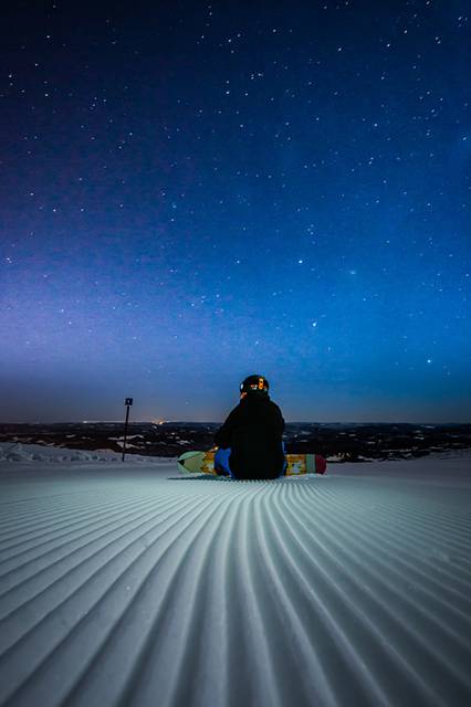 ゲレンデの星空を見つめるスノーボーダーの写真