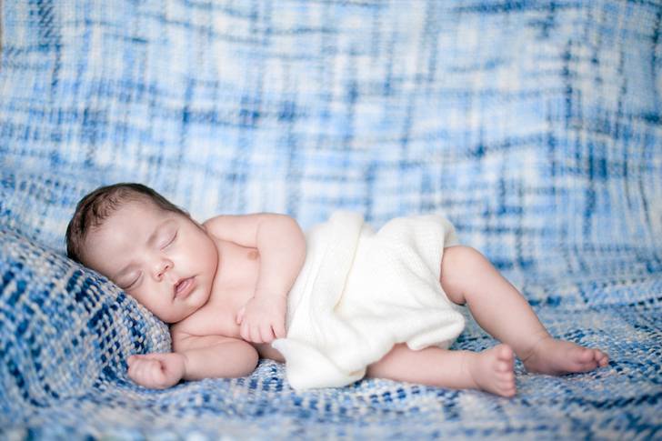 青い布の上で眠る赤ん坊
