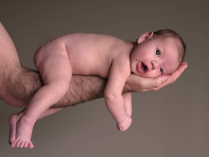 腕の上の裸の赤ちゃんの写真