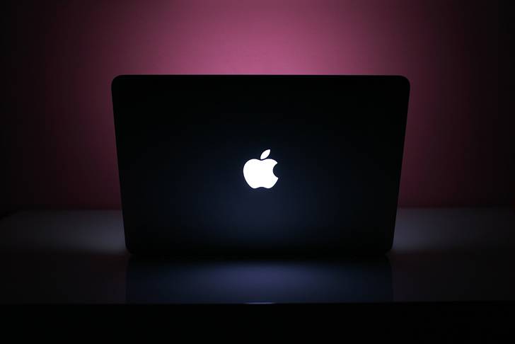 紫の壁を照らすMacBookの画像素材