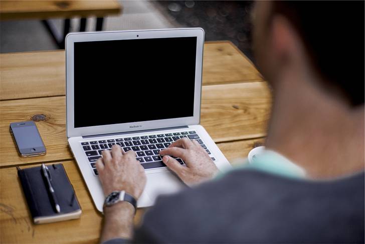 MacBookを使う男性の後ろ姿の写真